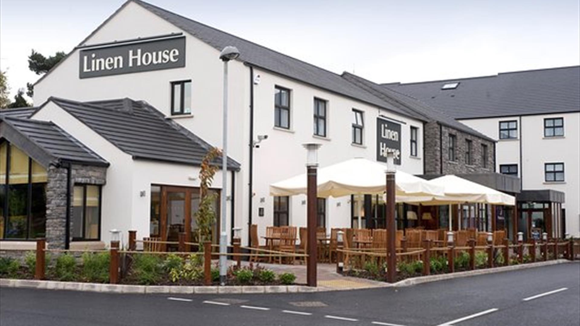 Image shows the exterior white building of Premier Inn Table Table Restaurant with a sign showing Linen House in grey and white writing and outside wo
