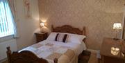 Image shows double bedroom with bedside table and lamp plus dressing table, mirror and lamp.