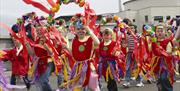Image shows a parade of brightly dressed children