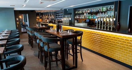 Image shows the Cardan bar with yellow brick front and an extensive seating area with low seating and tables and higher bar stool area