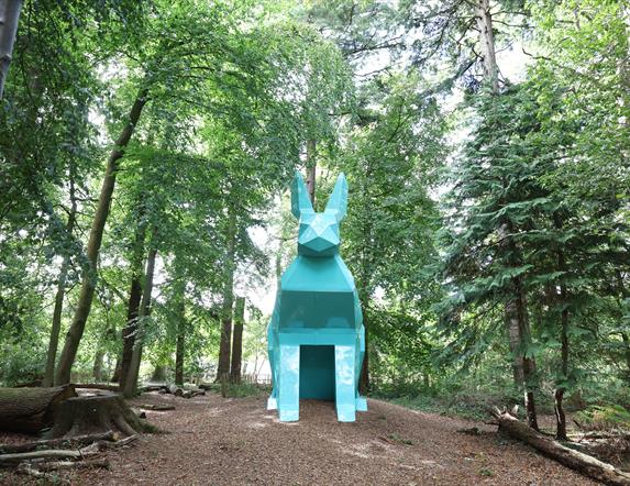An image of Peep the Hare part of the digital sculpture trail, the hare is teal and is located in the forest park.