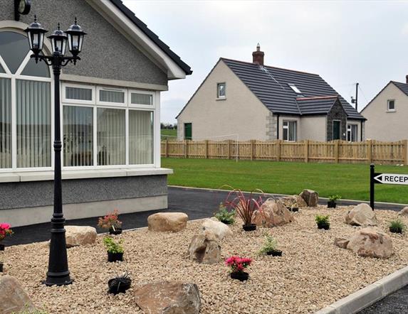 Image shows front of cottages with sign pointing to Reception