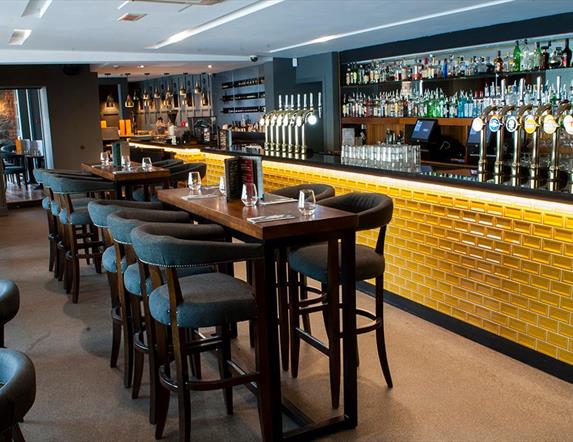 Image shows the Cardan bar with yellow brick front and an extensive seating area with low seating and tables and higher bar stool area