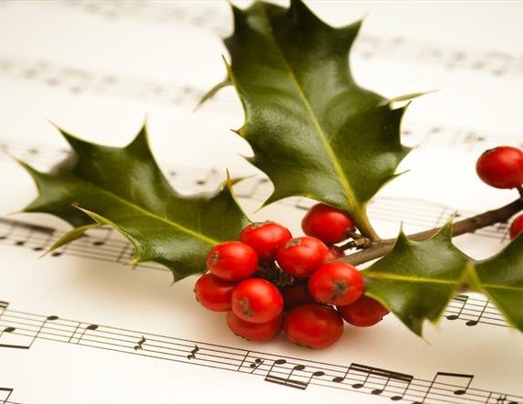 Image shows holly with berries and music sheet
