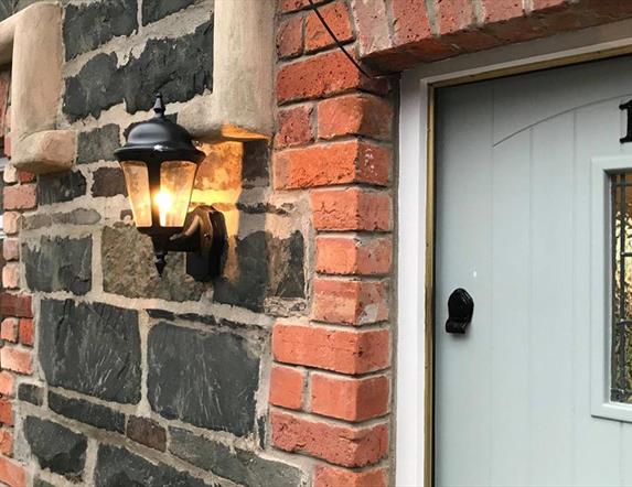 Image shows front door of No 16 with lantern on the brick wall outside