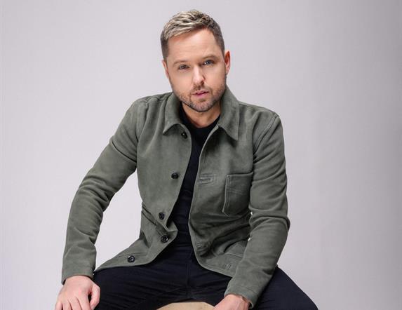 Image shows Derek Ryan sitting on stool.