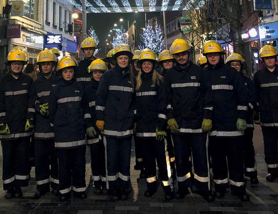 Fire Fighters standing in a row under the Christmas Lights in Bow Street
