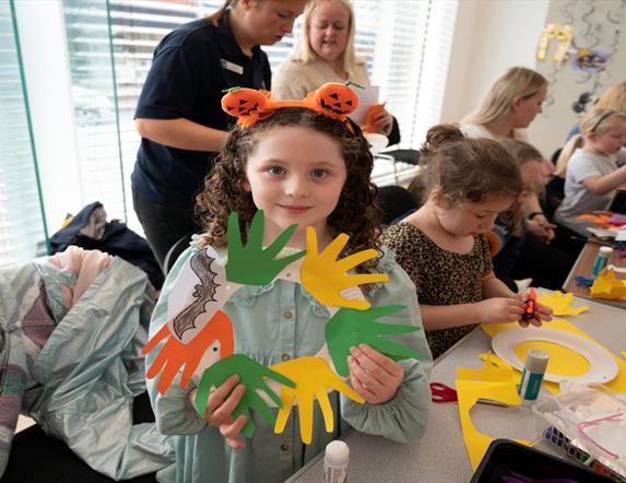 Image shows children's workshop and girl holding up workshop wreath display