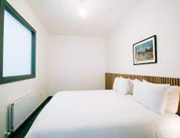 Image is of double bed with art and large TV on the wall