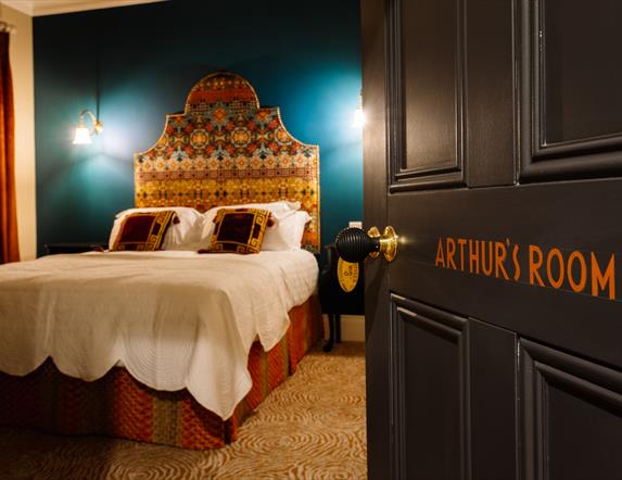 Picture of Arthur's suite inside Arthur's Guesthouse with carefully made double bed and side lamps on the walls