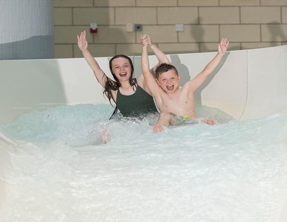 Image shows two children coming down slide in LeisurePlex