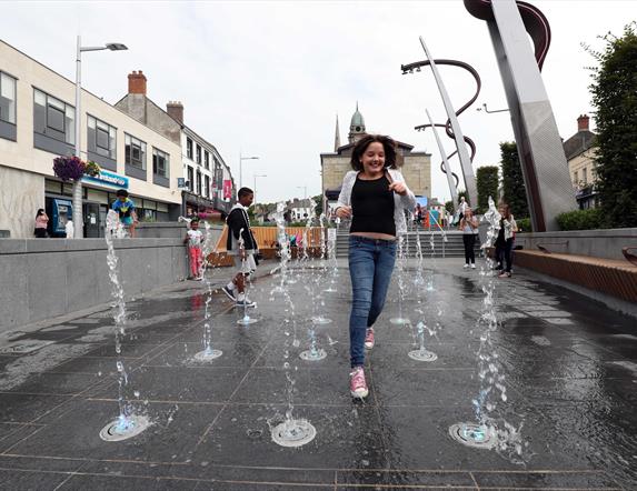 Girl running through fountains in Market Square, Lisburn