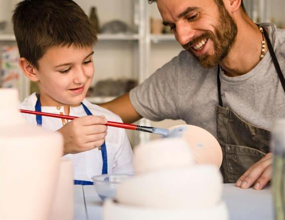 Image shows Father and Son painting pottery.