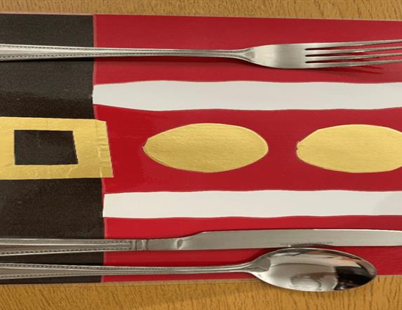 Image is of a festive place mat with cutlery