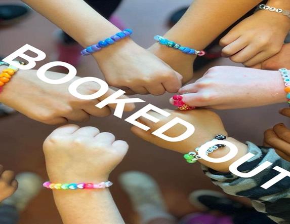 Image shows lots of hands in a circle with colourful bracelets on wrists.