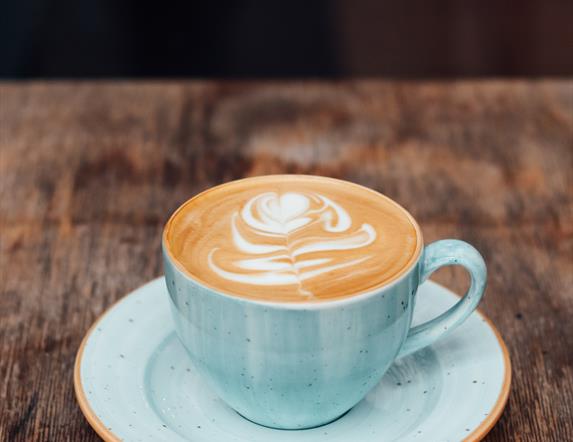 Image shows cup & saucer with latte coffee