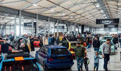 Image is of various cars and visitors at DUBSHED show in the Eikon Exhibition Centre LIsburn