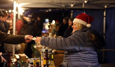 Lady with Santa hat selling at a stall at Christmas Market