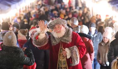 Santa waving with people shopping at Market behind him