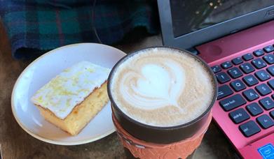 Image is of a cup of coffee and slice of cake in Ground Espresso