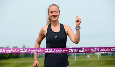 Image is of a female running and reaching the end of a race