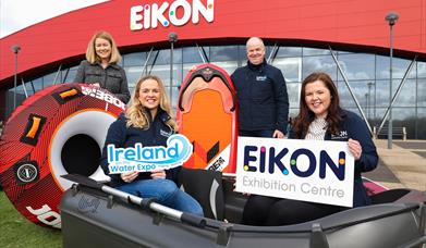 Image is of the organisers of the Ireland on the Water Expo in a dinghy and holding a surfboard outside the Eikon Exhibition Centre