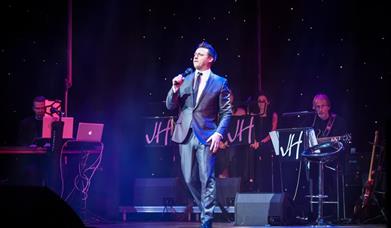Image is of singer James Huish performing on stage