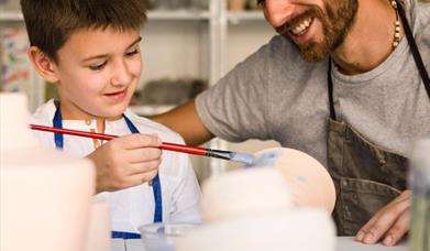 Image shows Father and Son painting pottery.
