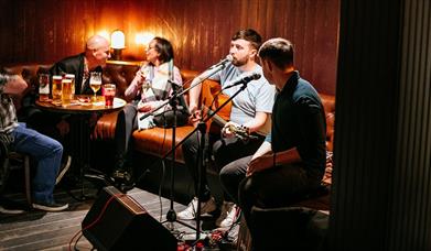 People enjoying drinks while band plays live music