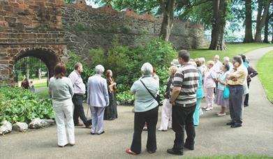 Image is of people on a guided tour of Castle Gardens