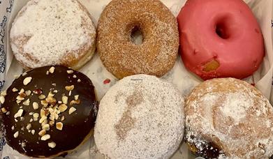 Image shows a box of 6 different donuts