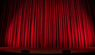 Picture of red curtains on a theatre stage