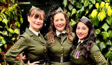 Image shows 3 swing girls dressed in green military style uniform