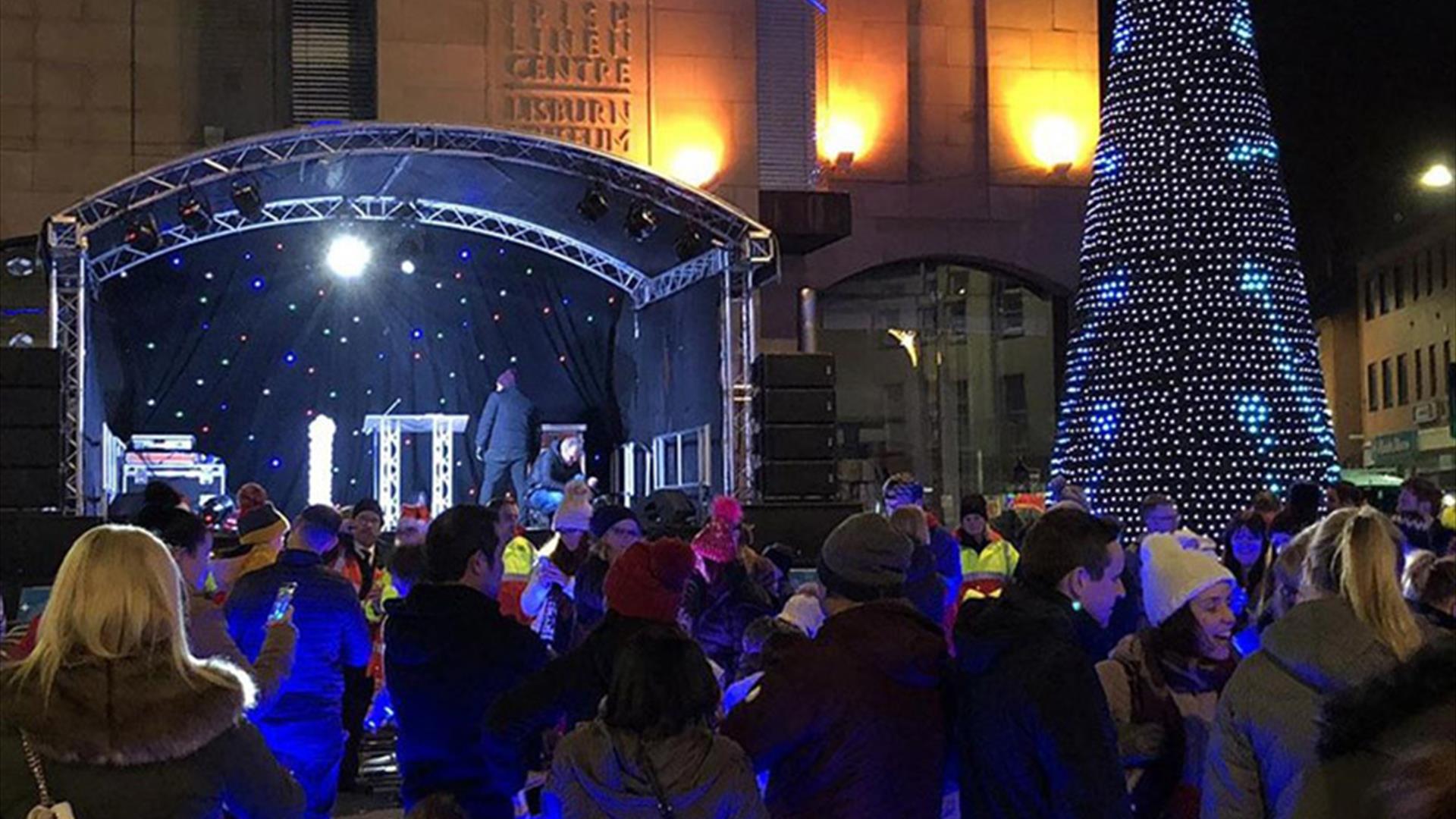 Persons gathered around the stage and Christmas tree