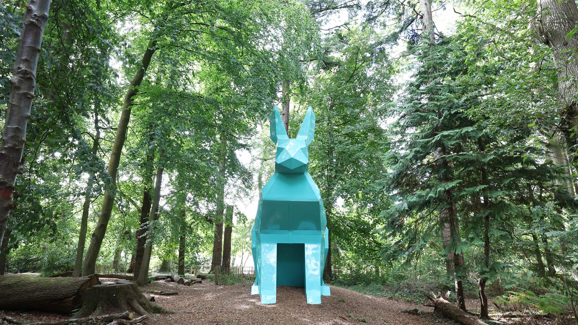 An image of Peep the Hare part of the digital sculpture trail, the hare is teal and is located in the forest park.