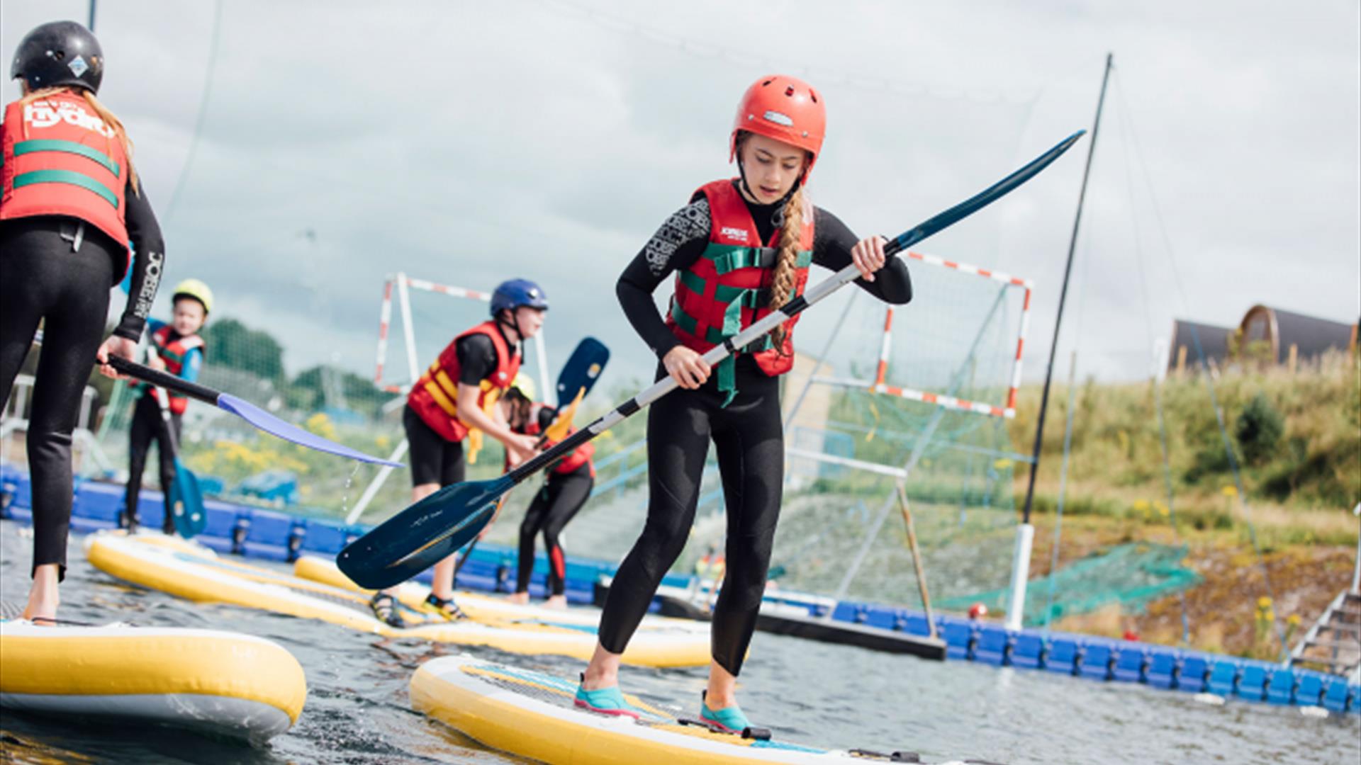 Image shows children playing on paddle boards