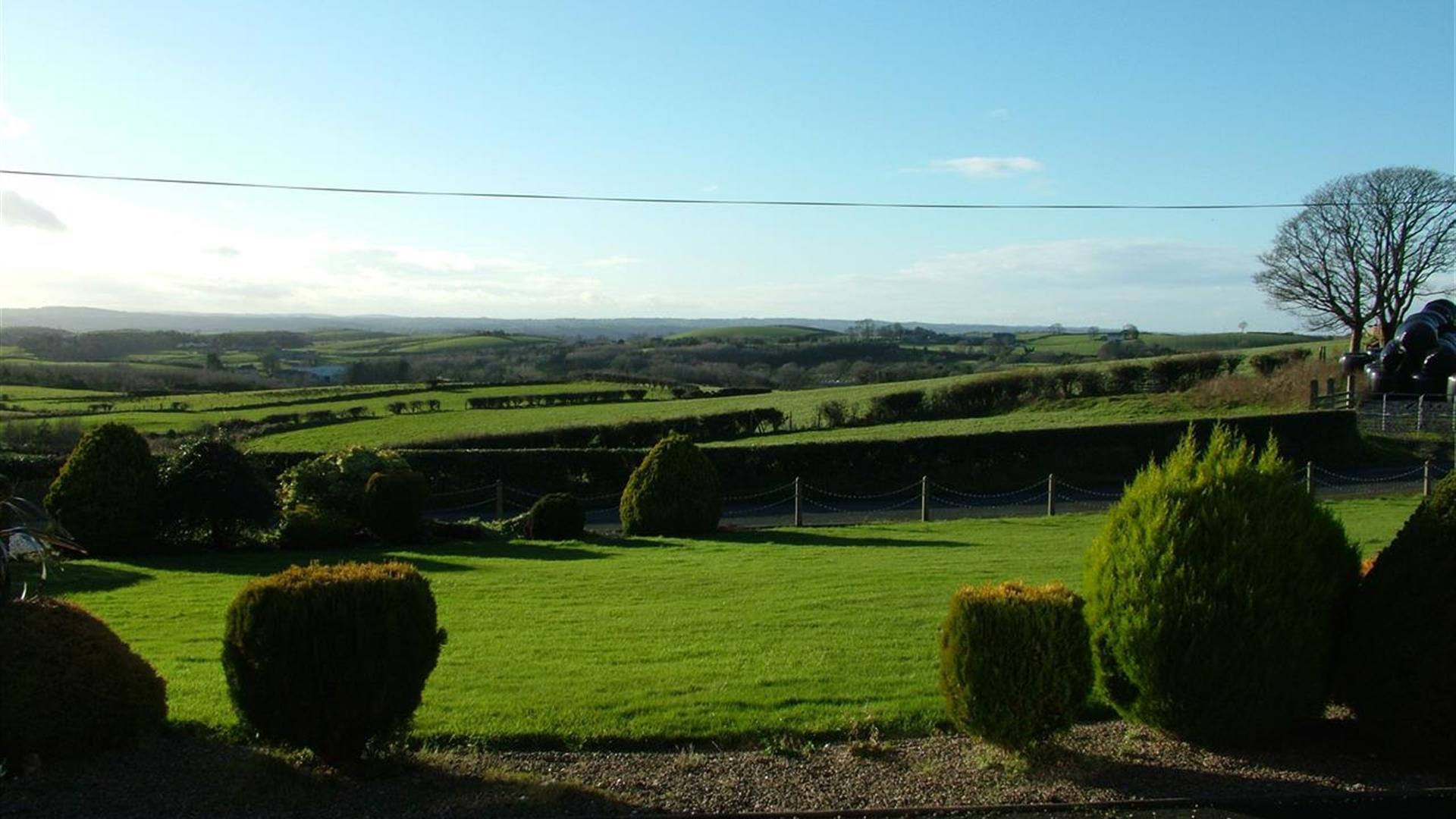 Image shows lawn in front of property with view of the countryside beyond