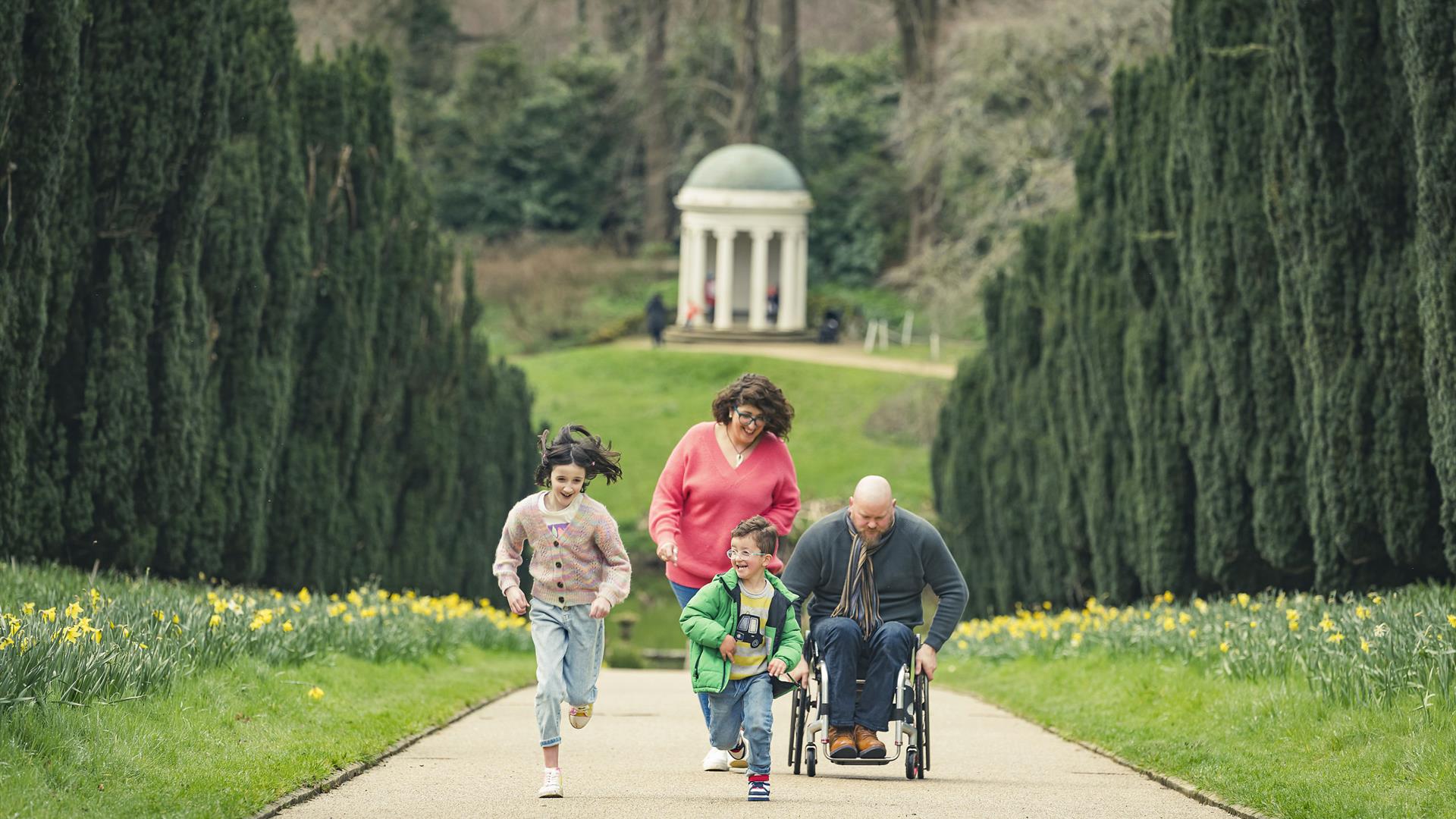 A family are walking up Yew Tree Walk at Hillsborough Castle and Gardens