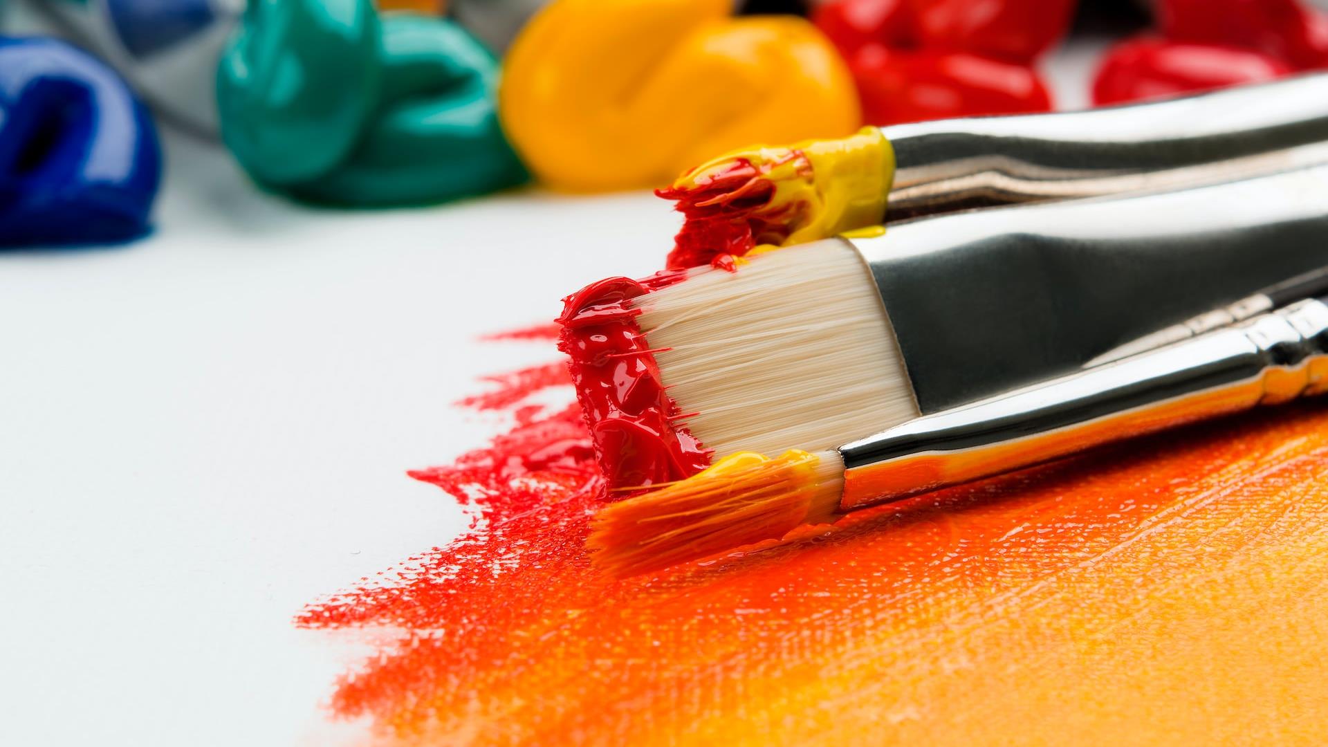 Paint brushes with pain on them and blogs of paints in the background