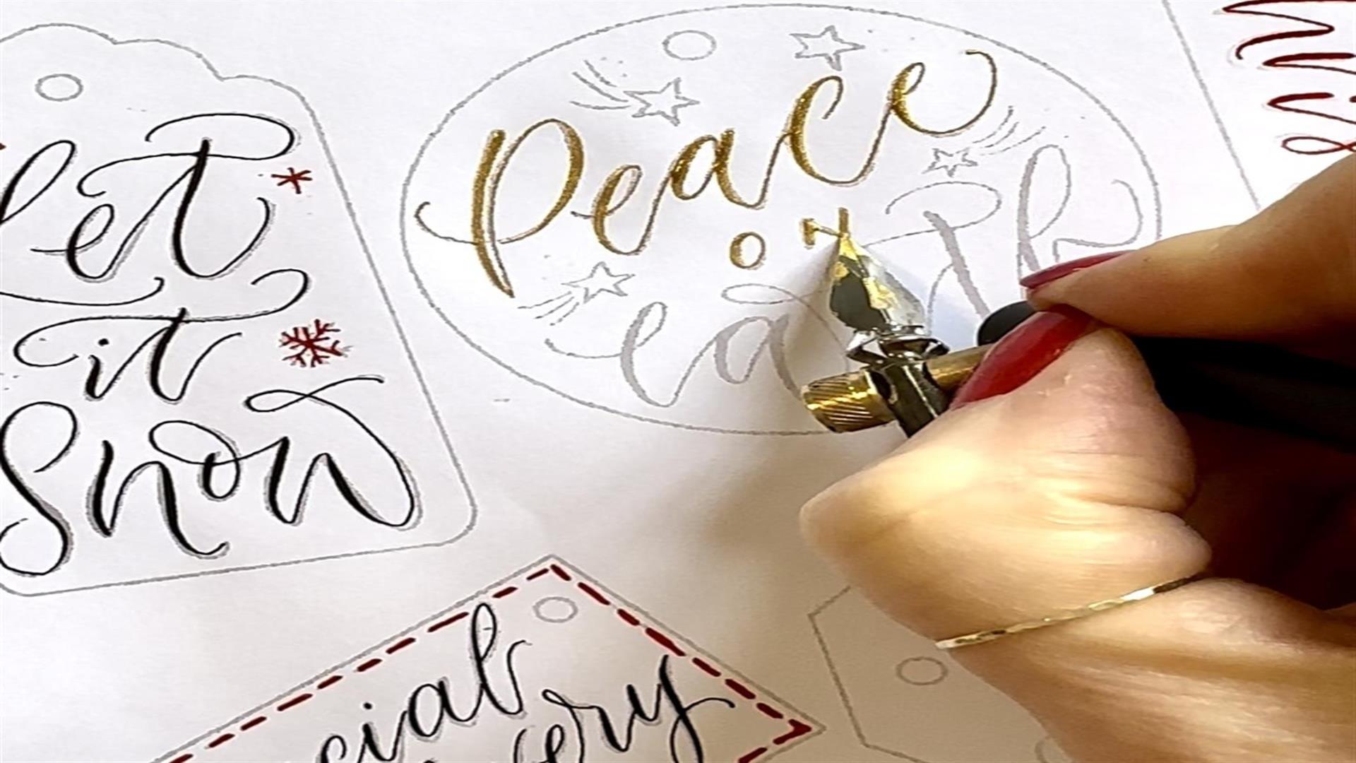 Image shows someone producing Calligraphy in gold writing.
