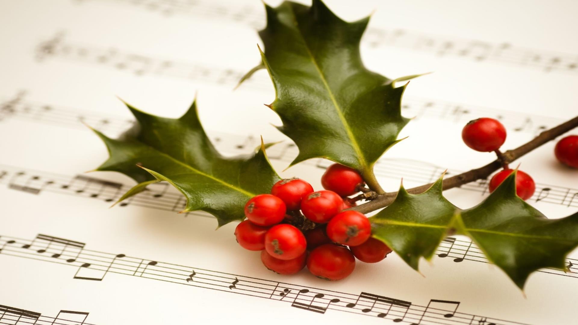 Image shows holly with berries and music sheet