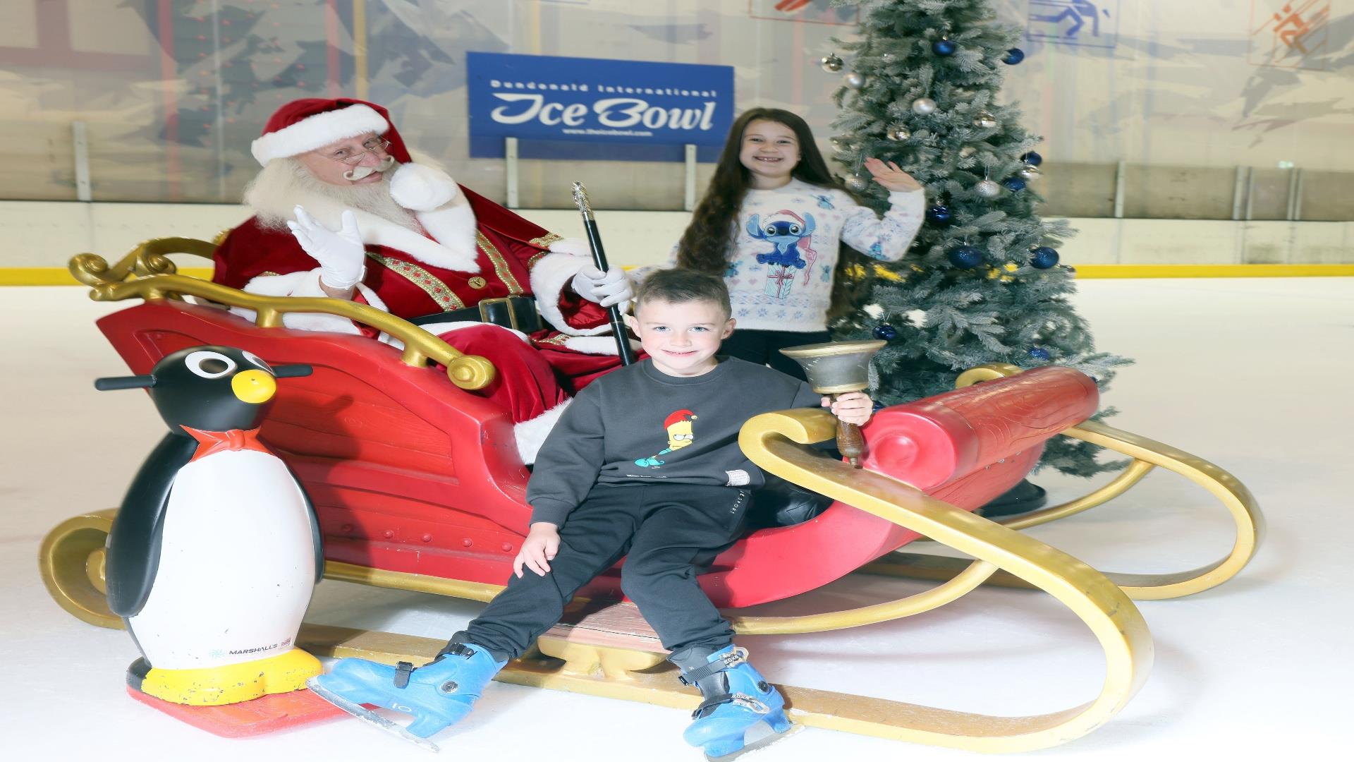 Santa Claus on a sleigh on the ice rink with two children at Dundonald International Ice Bowl