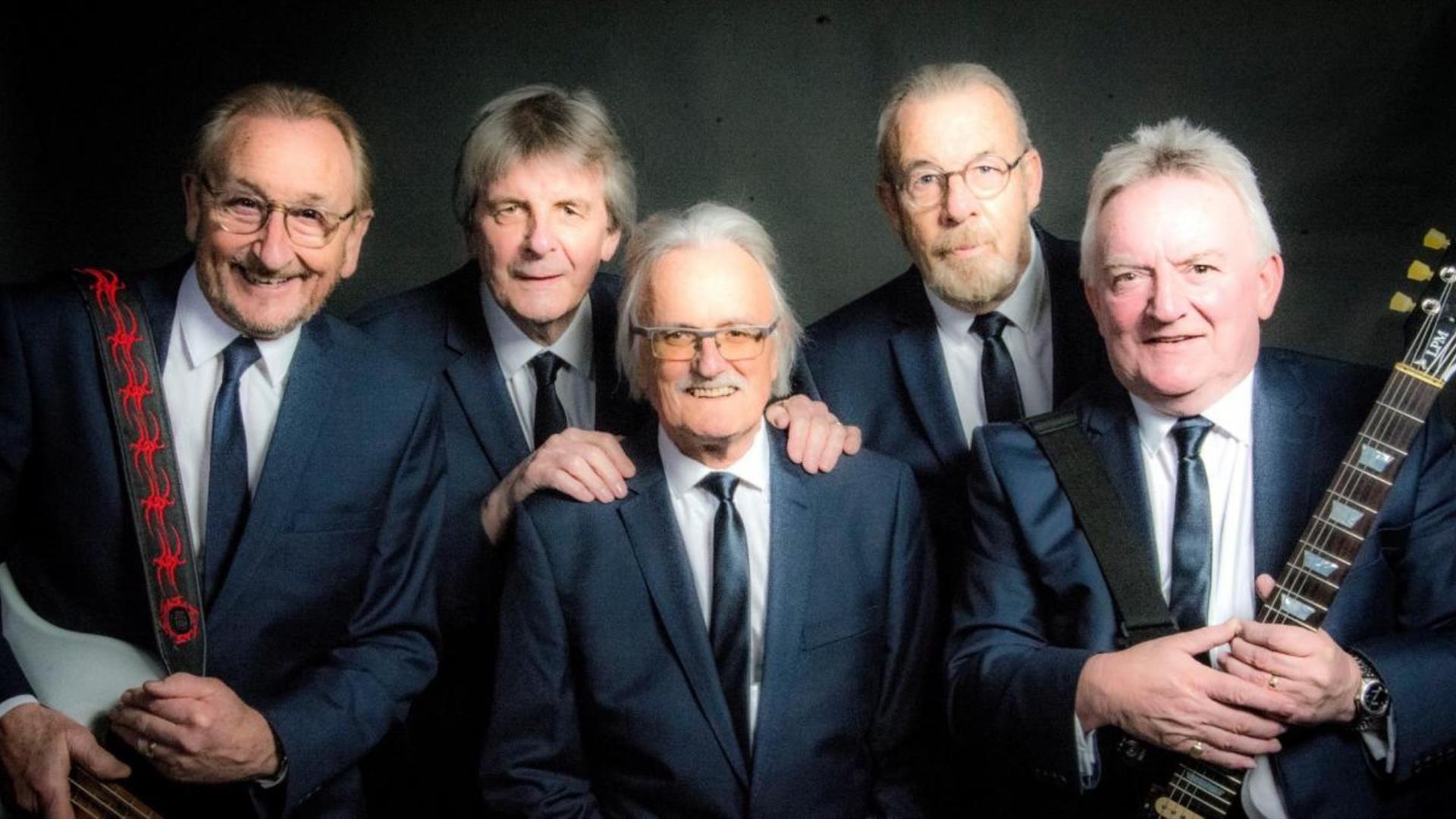 5 men in suits with guitars