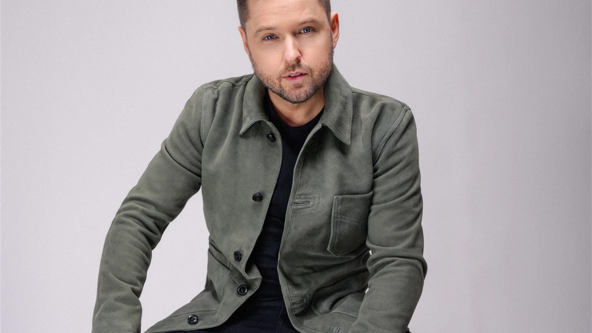Image shows Derek Ryan sitting on stool.