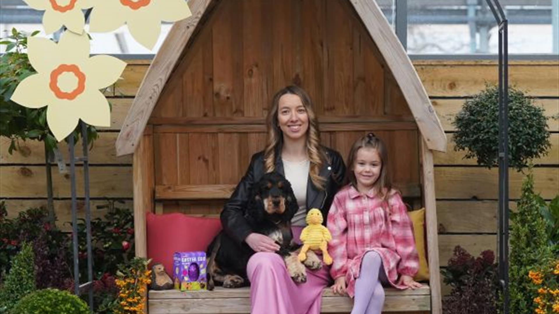 Image of Woman, girl and Dog sitting with Easter treats around them.