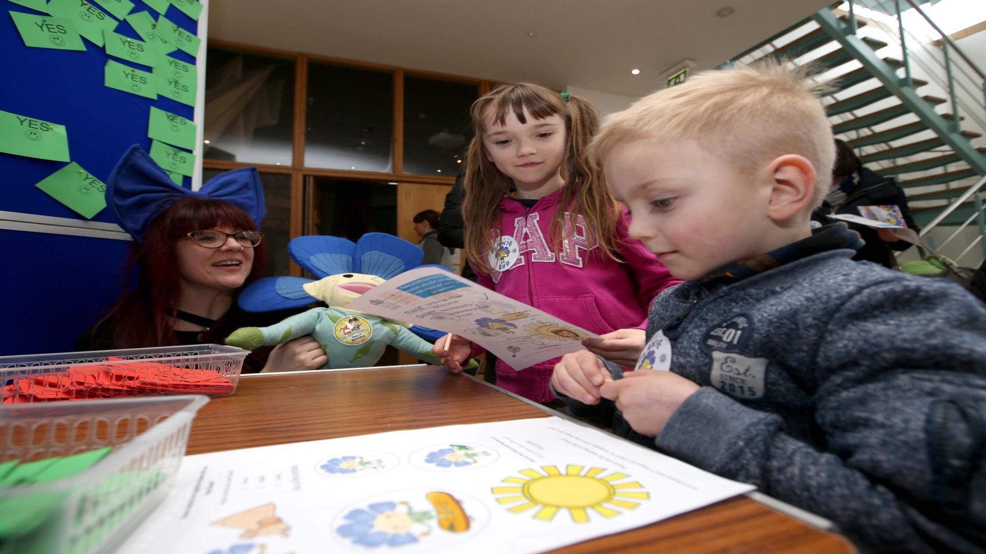 Image shows children sitting at a table looking at the Flaxie Trail