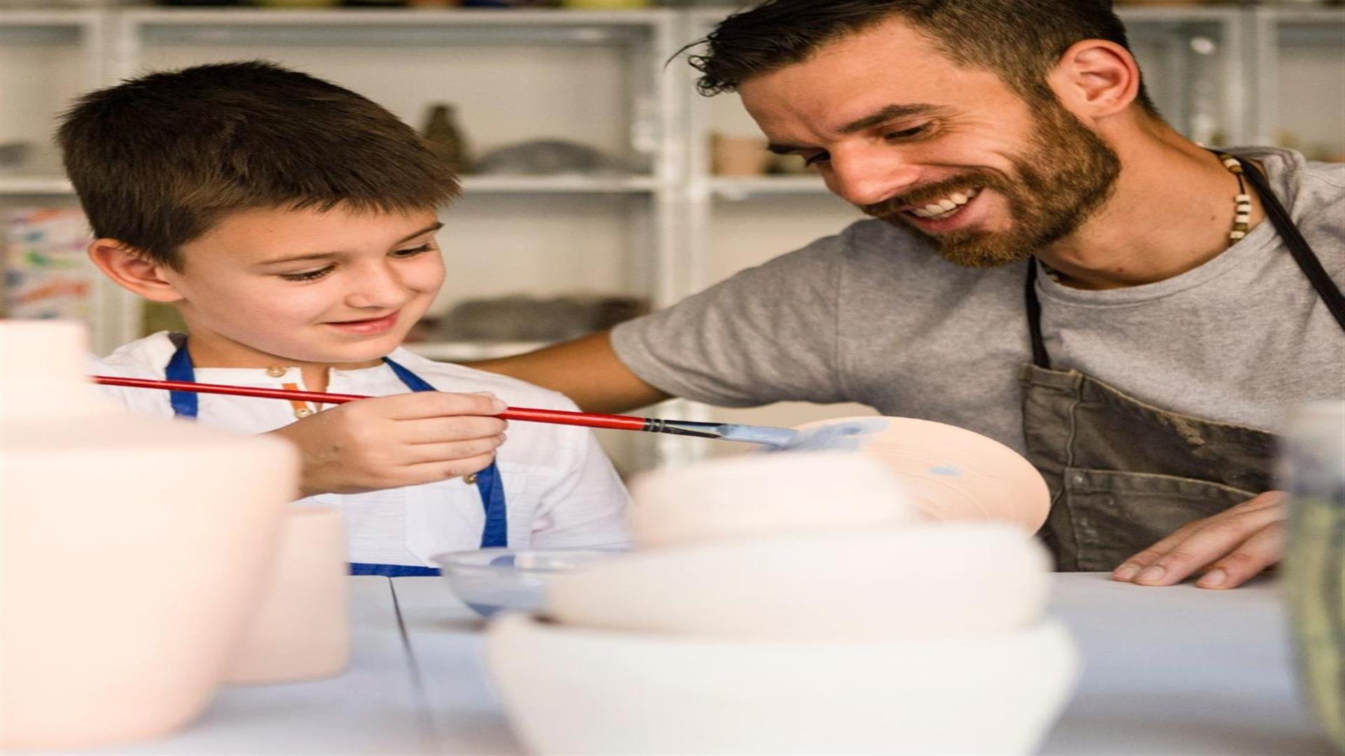 Image shows father and painting pottery.