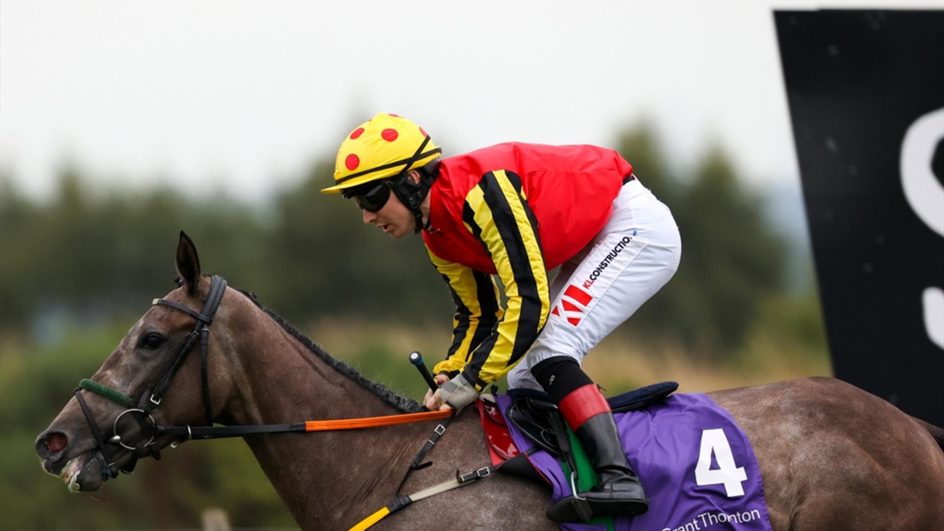 Jocket wearing red top riding horse