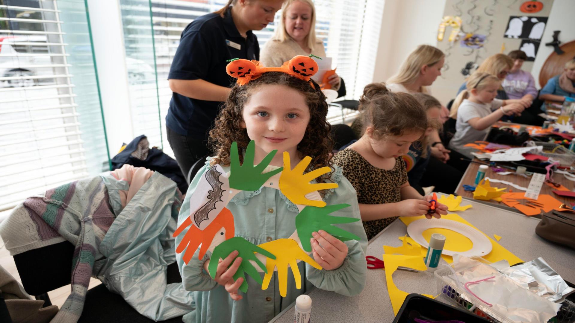Image shows children's workshop and girl holding up workshop wreath display