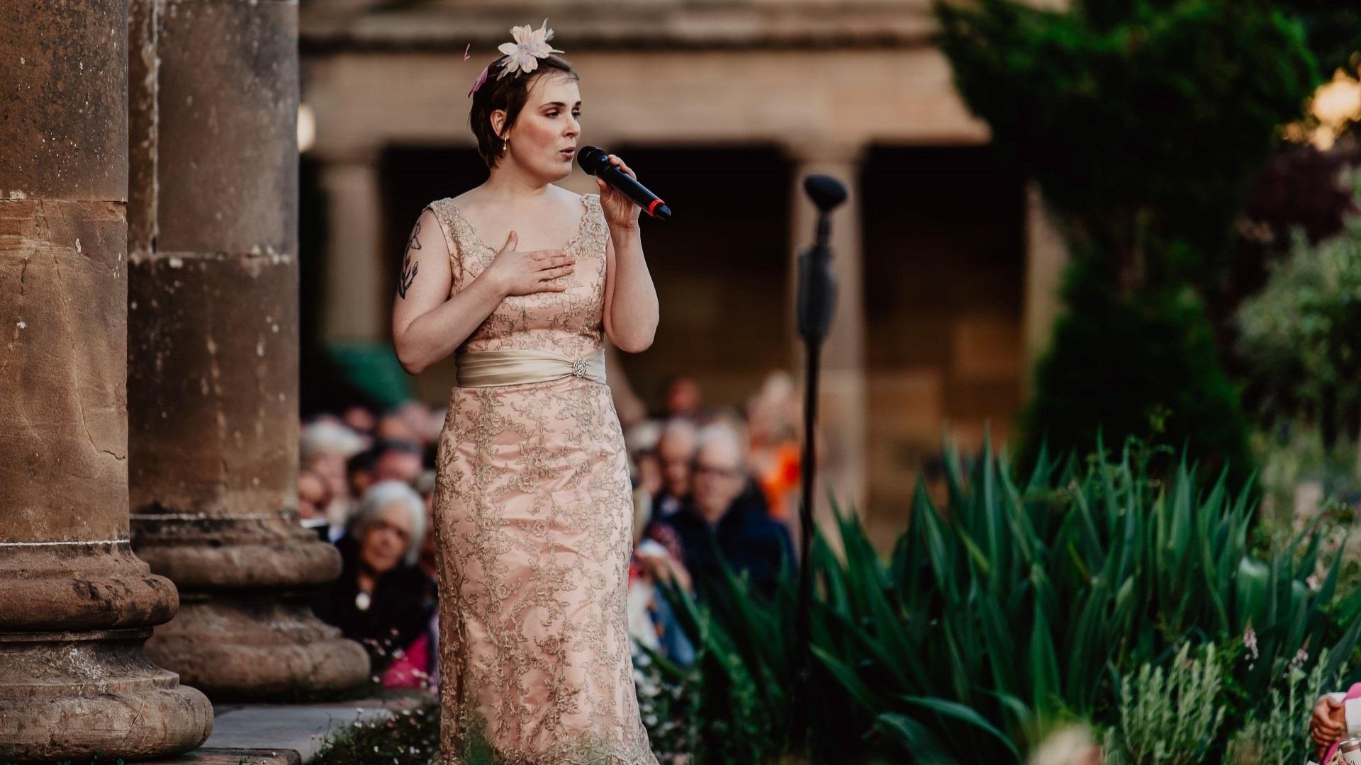 Image shows a singer performing outside in Hillsborough Gardens.